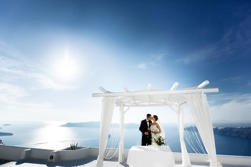 Bride and groom kissing with the ocean behind them. 