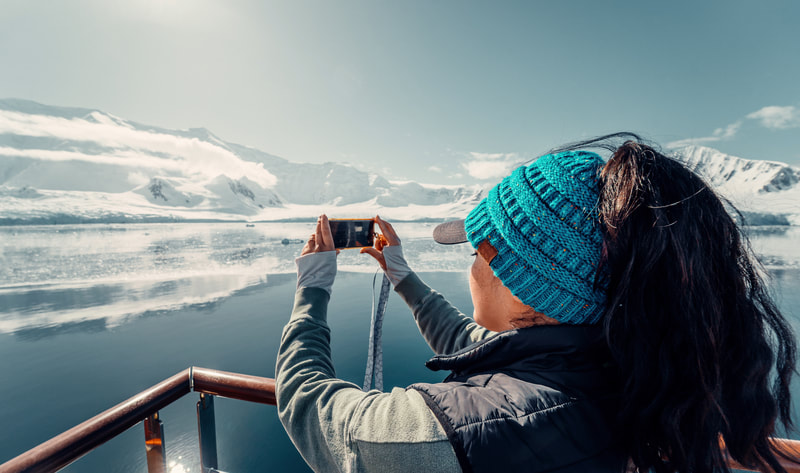 Woman taking a picture of a glacier. 
