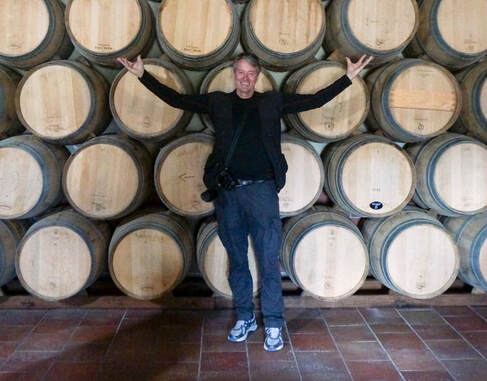 Man standing in front of wine barrels in Bordeaux France.  