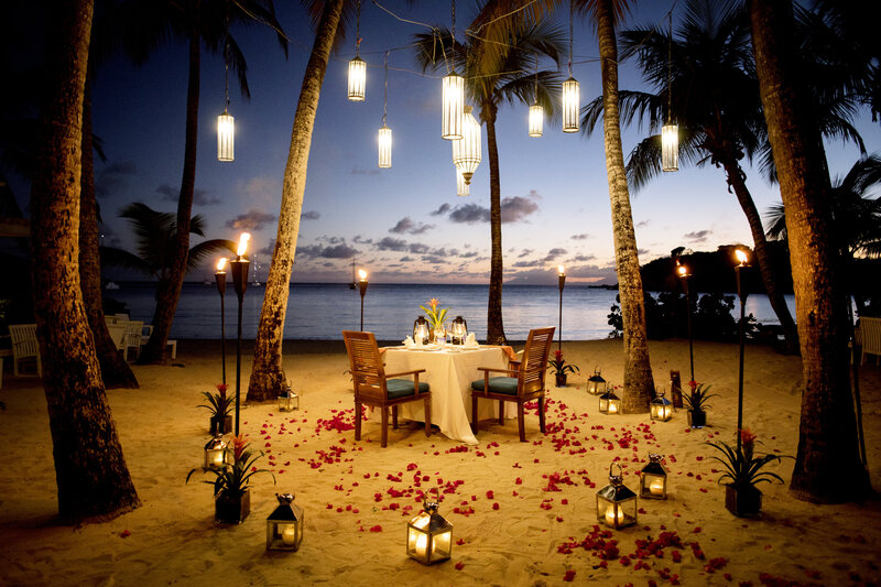 Romantic candlelit dinner on beach under palms